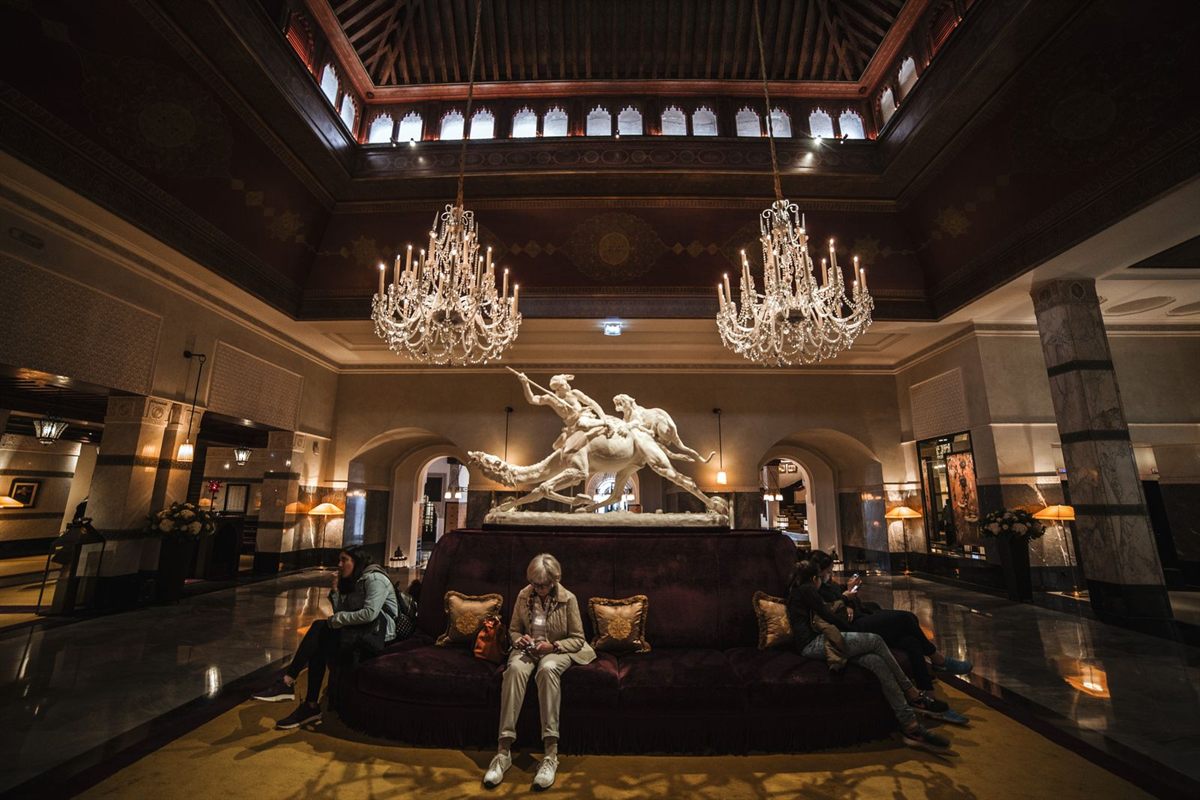 A grand hotel lobby with chandeliers and a sculpture at its centre