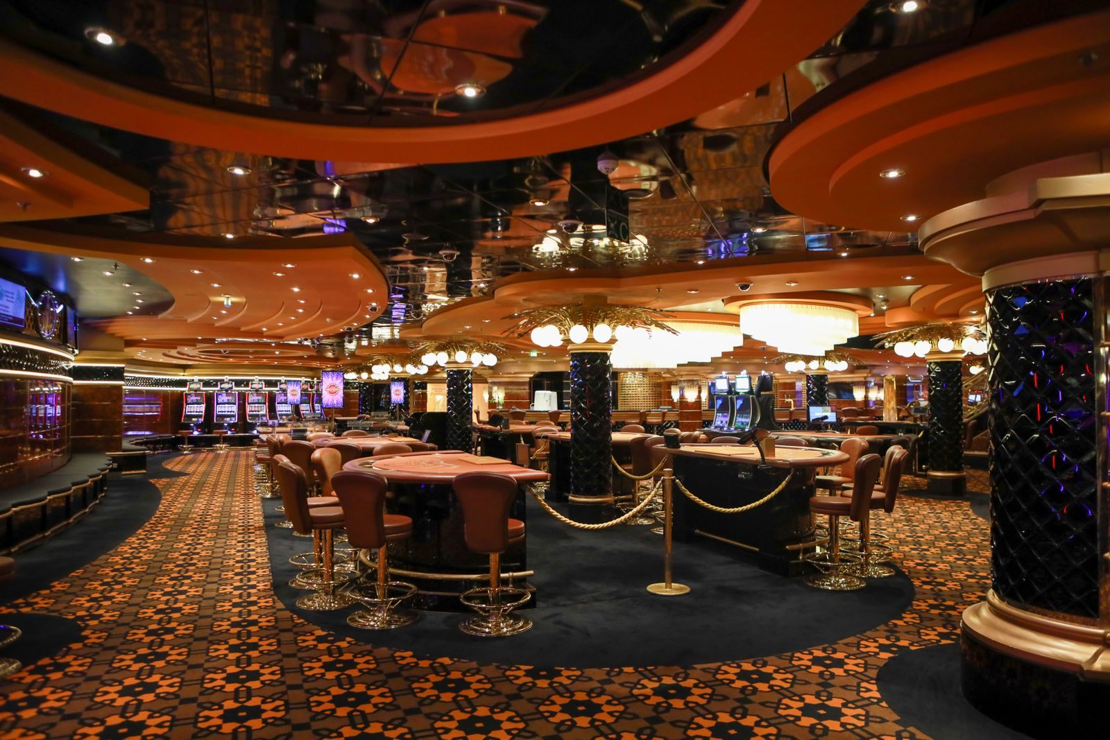 The casino on a cruise ship, with gaming tables and a patterned carpet, where casino cruise travel rewards begin