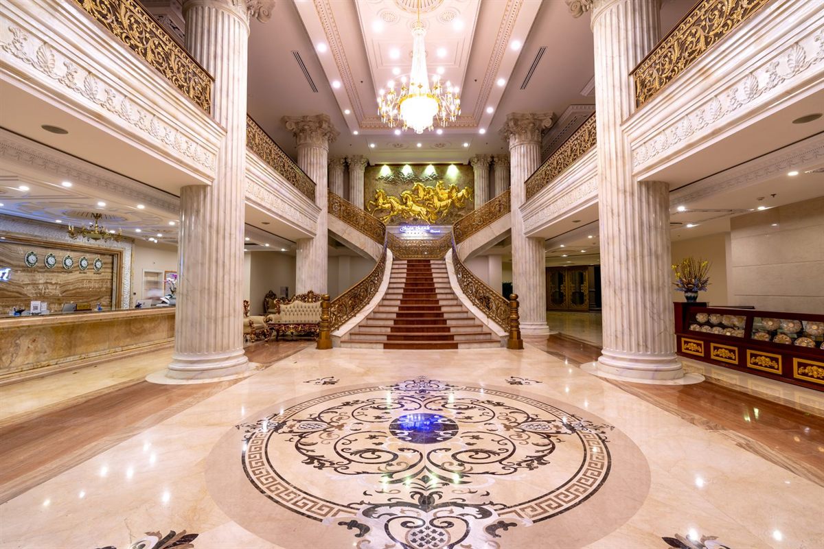 A grand marble hotel lobby with columns and a sweeping staircase